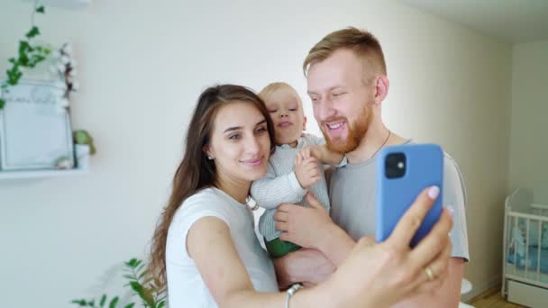 Padres felices con bebé niño tomando foto selfie en casa — Vídeos de Stock