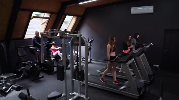 Group of athletic people training on treadmills and bikes in gym — Stock Video