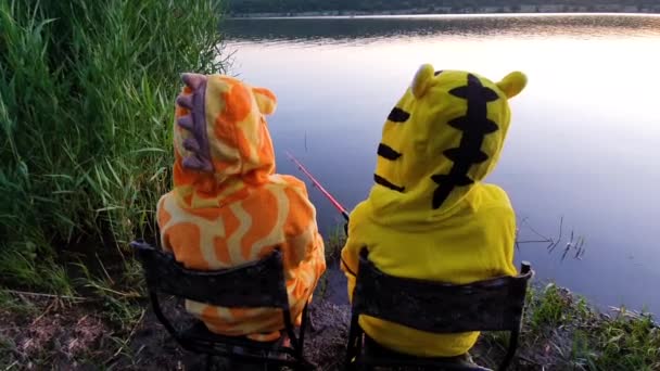 Kleine Mädchen im lustigen Pyjama angeln am Fluss bei Sonnenuntergang — Stockvideo