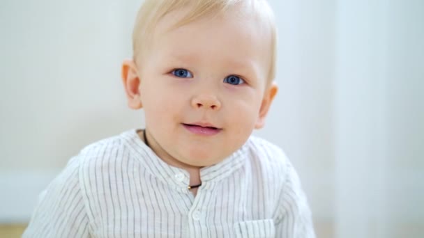 Menino com olhos azuis e cabelo loiro sorrindo para a câmera — Vídeo de Stock