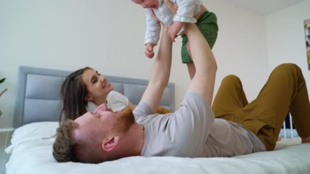 Padres felices jugando con el niño en el dormitorio — Vídeos de Stock