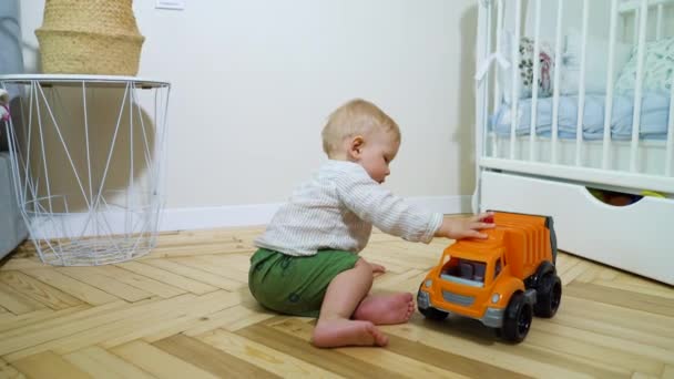 Barefoot tout-petit garçon jouer avec jouet voiture dans la chambre — Video