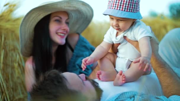 Família feliz com bebê se divertindo durante piquenique no campo de trigo — Vídeo de Stock