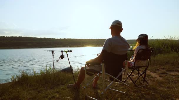 Padre e figlia pesca sulla riva del fiume al tramonto — Video Stock