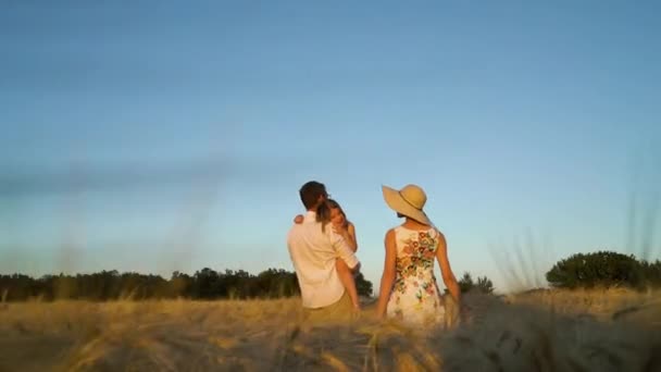 Втомилася дитина на руках батька в пшеничному полі на заході сонця — стокове відео