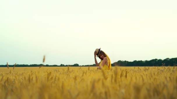 Romantisches Mädchen spielt im Sommer mit Strohhut im Weizenfeld — Stockvideo