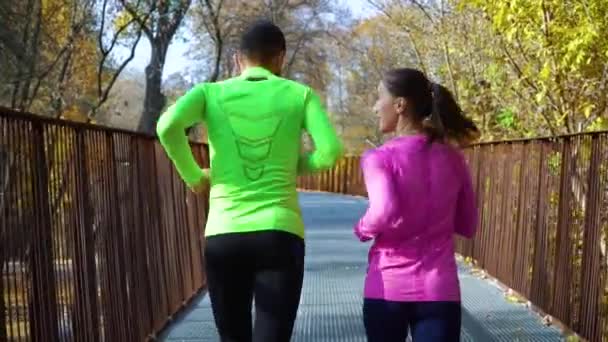 Atletisch gezin joggen over moderne brug in de herfst — Stockvideo