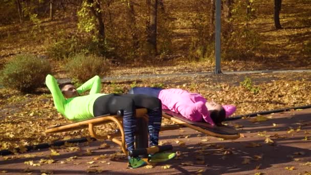 Pareja joven en forma haciendo ejercicio en el campo de deportes en otoño — Vídeo de stock