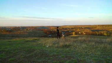Havacı kız ve köpeği Amerikan Staffordshire Teriyeri gün batımında tepede.