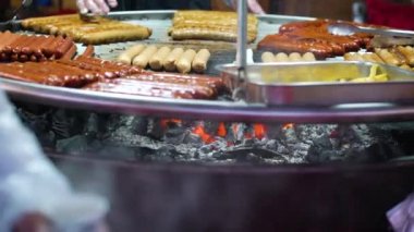 Üniformalı aşçılar tatil pazarında ızgara sosis pişiriyor.