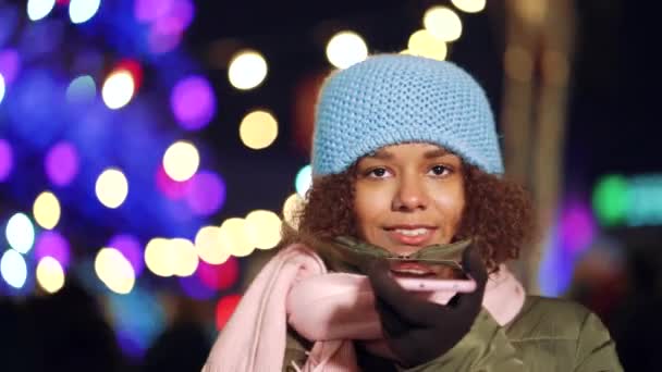 Joyful black girl looking around on holiday market and talking on phone — Stock Video