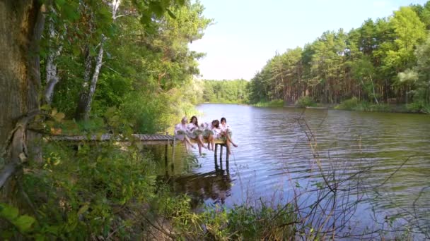 Lovely women in traditional Ukrainian dresses on pontoon bridge over river — Stock Video