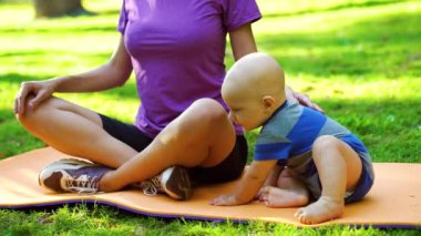 Bebek ve anne güneşli parkta yoga yapıyor.