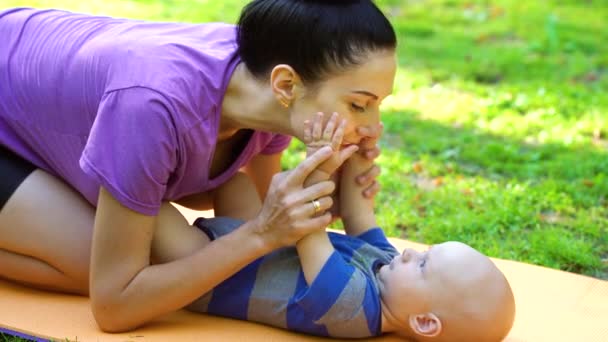 Anya játszik a baba feküdt szőnyegen a nyári parkban — Stock videók