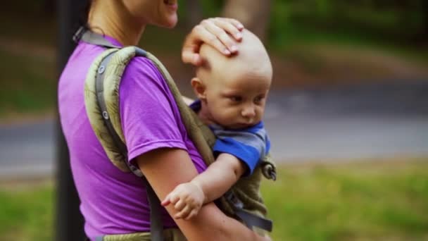 Liefdevolle Moeder wandelen met baby in sling in openbaar park — Stockvideo