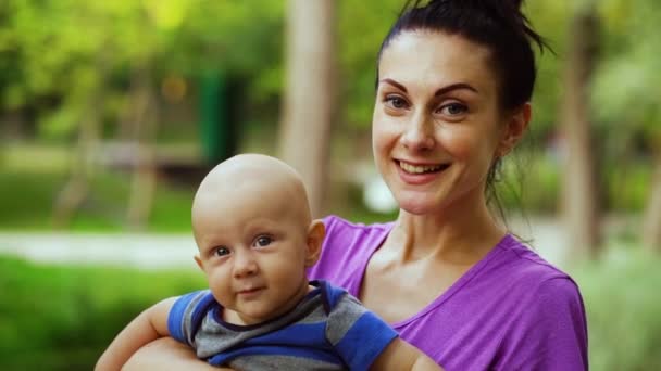 Šťastná matka drží a líbání dítě v parku — Stock video