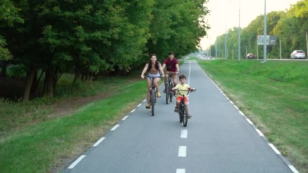 Rodzina rowerzystów jazda na torze rowerowym w pobliżu ruchliwej drogi miejskiej — Wideo stockowe