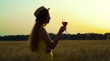 Gün batımında şarap içen kadın silueti.