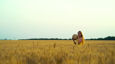 Sarışın kadın tarlada hasır şapkayla oynuyor.