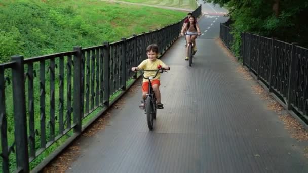 Счастливая семья пересекает металлический мост на велосипедах — стоковое видео