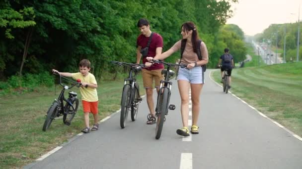 Familie wandelen met fietsen op fietspad in de buurt van bos — Stockvideo