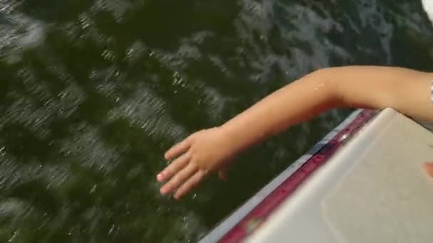 Ręka dziecka rozpryskująca wodę podczas żeglowania na łodzi — Wideo stockowe