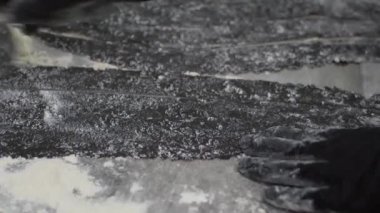 Siyah hamur dilimlerini pizza bıçağıyla kesmeye yakın çekim.