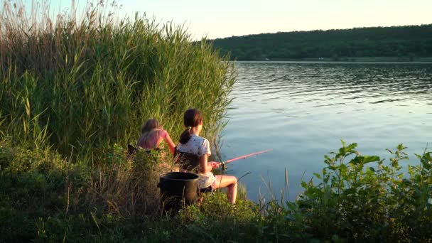 Les filles pêchent sur le bord de la rivière au coucher du soleil — Video