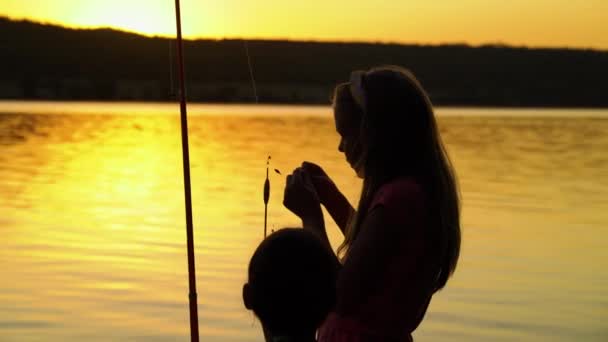 Siluet gadis memancing di tepi sungai saat matahari terbenam — Stok Video