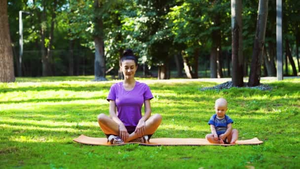 Matka a dítě dělají jógu v letním parku — Stock video