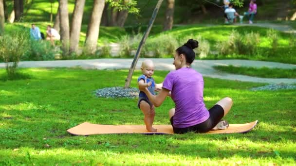 Fit vrouw zitten in het park en het houden van baby — Stockvideo