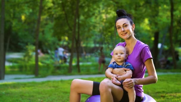 Fit maman et bébé équilibrage sur balle de fitness dans le parc — Video