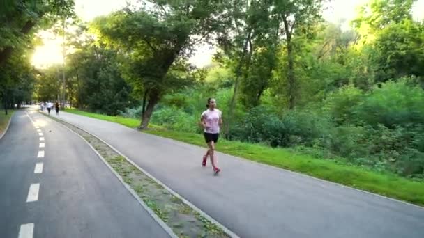 Mujer joven corriendo en el parque en el día soleado — Vídeos de Stock