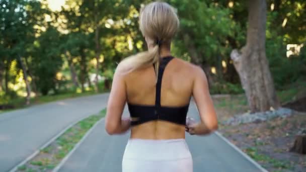 Mujer rubia corriendo en el parque verde por la mañana — Vídeos de Stock