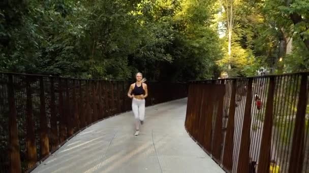 Sportliche Frau läuft über Metallbrücke — Stockvideo