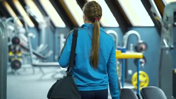 Kobieta wchodząca na siłownię i stawiająca torbę sportową na ławce — Wideo stockowe
