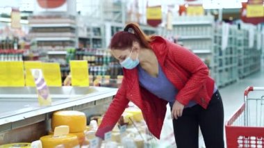 Tıbbi maskeli kadın dondurucudan peynir topluyor.