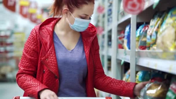 Женщина в маске покупает макароны в супермаркете во время пандемии — стоковое видео