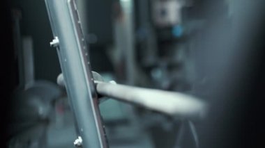 Kadın vücut geliştirici spor salonunda halterin üzerine ağırlık koyuyor.