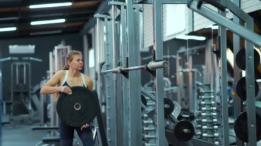 Spor salonunda ağırlık plakası takan bir kadın.
