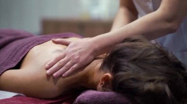 Sağlık merkezindeki kadının omuzlarına masaj yapan kadın elleri.