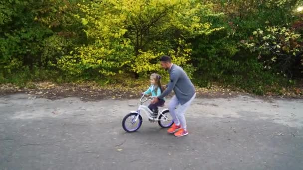 Ojciec uczy córeczkę jeździć na rowerze w parku — Wideo stockowe
