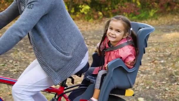 Девушка в детском кресле на велосипеде смеется, пока отец ездит на велосипеде — стоковое видео