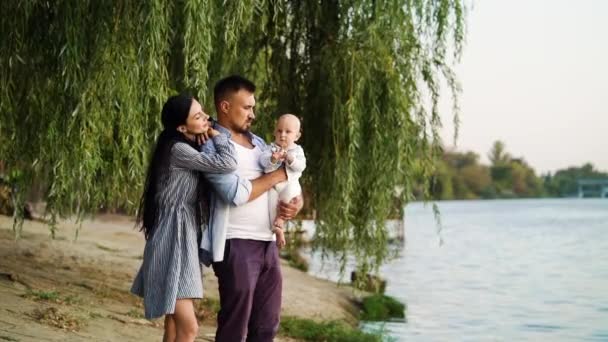 川の近くに立っている赤ん坊を持つ親 — ストック動画