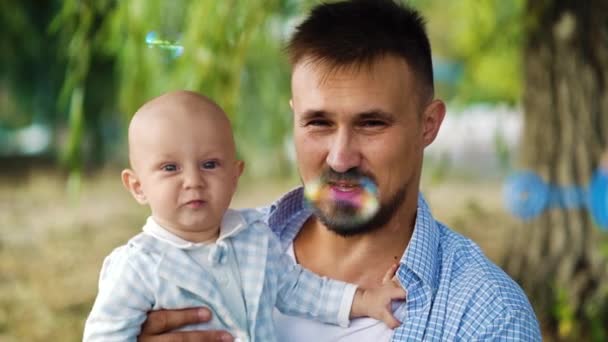 Pai segurando bebê e mãe soprando bolhas — Vídeo de Stock
