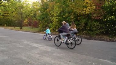 Sonbahar parkında bisiklet süren sportif bir aile.