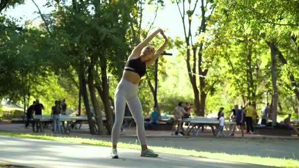 Kvinna värmer upp innan jogging i sommarparken — Stockvideo