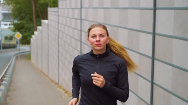 Sportliche Frau joggt in leerer Stadt nahe Straße — Stockvideo