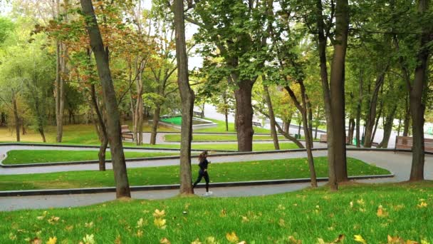 Kvinnan springer ner gångväg i parken i början av hösten — Stockvideo