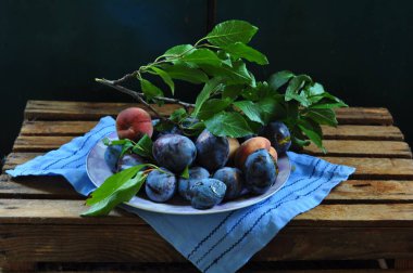 Ahşap bir masada mavi bir tabak erikli erikler.